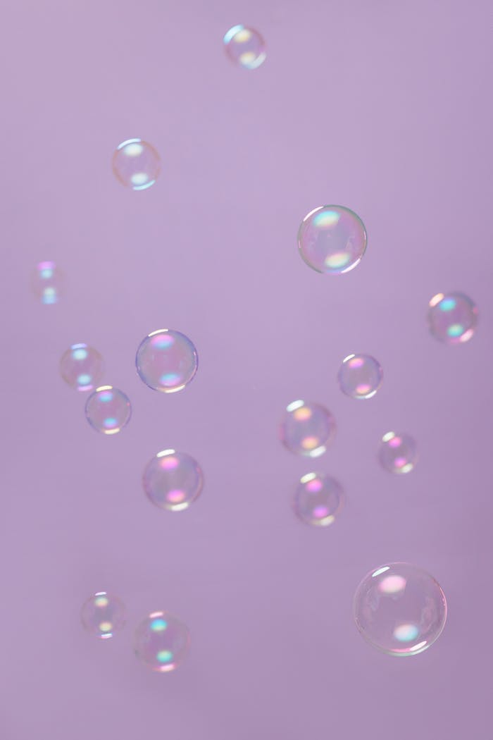 Floating soap bubbles against a serene lilac background emphasize purity and playfulness.